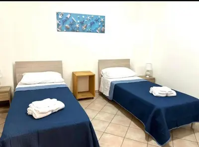 two beds in a room with towels on them at Nelly's house in Terrasini
