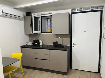 a kitchen with white cabinets and a table and a yellow chair at La dolce casa in Palermo