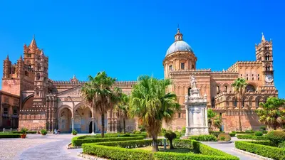 a large building with a clock tower and palm trees at GAle Apartment in Palermo