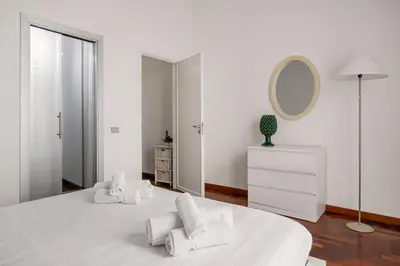 a white bedroom with a large white bed and a mirror at Cortile Benso Guest House in Palermo