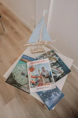 a pile of books sitting on the floor next to a toy boat at La Perla d'Argento in Santa Flavia