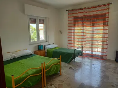 a bedroom with two beds and a large window at Aura azzurra in Carini