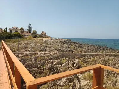 a wooden stairway leading to a rocky beach with the ocean at Aura azzurra in Carini