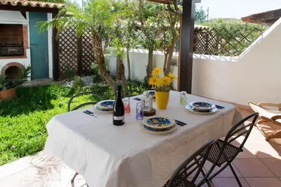 a table with a bottle of wine and plates on it at Anemos Apartment - Villa Stella in Macari