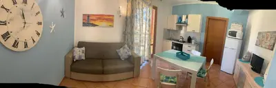 a living room with a chair and a clock on the wall at La perla marina casa vacanza in San Vito lo Capo