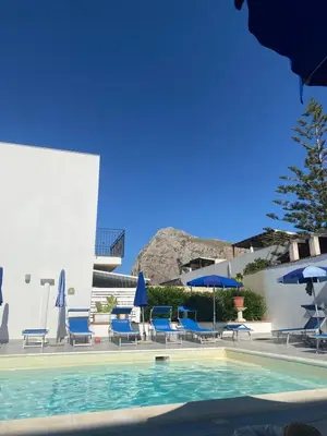 a swimming pool with blue chairs and umbrellas at La perla marina casa vacanza in San Vito lo Capo