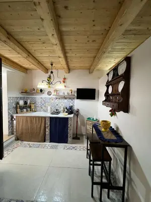a kitchen with wooden ceilings and a table with chairs at Maddy Luxury Apartment in Palermo