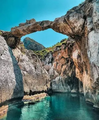 an arch in the rocks in a body of water at Casa U' Rittu Filu in Bagheria