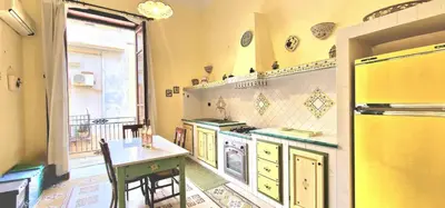 a yellow kitchen with a table and a stove at Casa De Gasperi in Castellammare del Golfo
