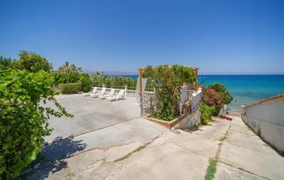 a patio with chairs and the ocean in the background at 3 Bedroom Lovely Apartment In Trappeto in Trappeto