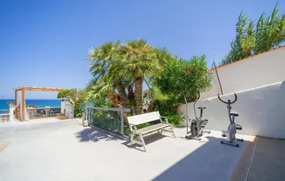 a patio with a bench and exercise equipment next to a palm tree at 3 Bedroom Lovely Apartment In Trappeto in Trappeto