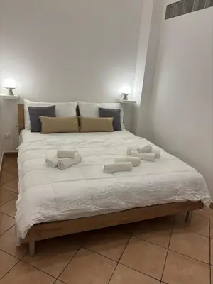 a large white bed with three towels on it at Helios Apartaments in Cinisi