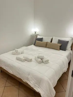 a large white bed with three towels on it at Helios Apartaments in Cinisi