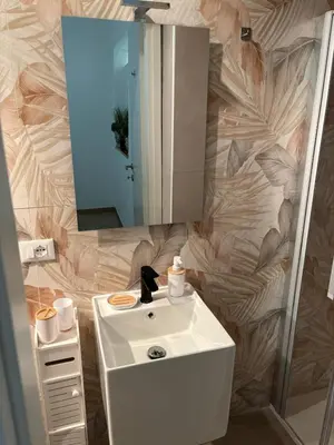 a bathroom with a white sink and a mirror at Helios Apartaments in Cinisi