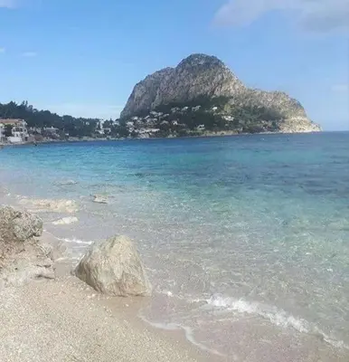 a beach with a rock in the water at Giomasue' in Porticello