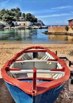 a red and blue boat sitting on the beach at Giomasue' in Porticello