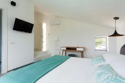 a white bedroom with a bed and a television at White Luxury Villa by Le Dhome Sicily in Partinico