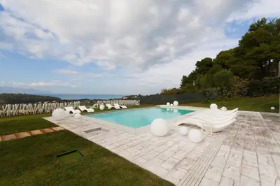 a swimming pool with lounge chairs in the grass at White Luxury Villa by Le Dhome Sicily in Partinico
