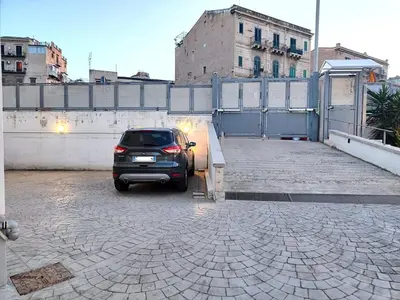 a car parked in a parking lot next to a fence at QASA apartment with terrace, Palermo center in Palermo