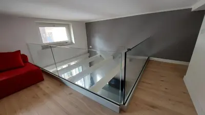 a glass staircase in a room with a red couch at AntoX3 in Palermo