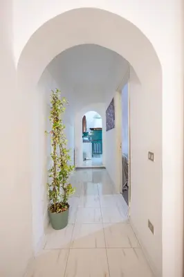 a hallway with white walls and a plant in a pot at Plaza Del Mar Casa vacanza Mondello in Palermo