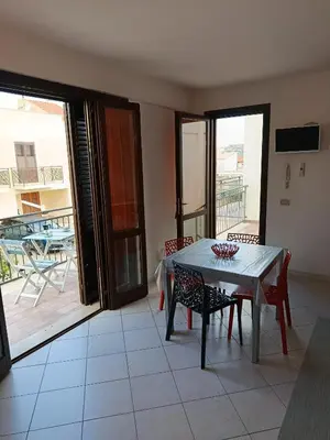 a dining room with a table and chairs and a balcony at Relax beach San Vito lo Capo in San Vito lo Capo