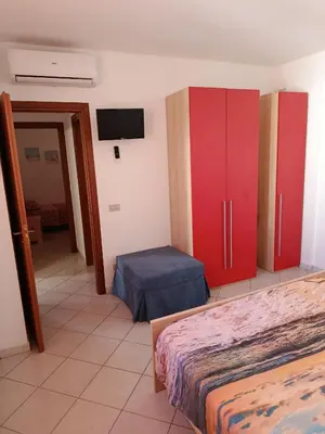 a room with two beds and a tv and red cabinets at Relax beach San Vito lo Capo in San Vito lo Capo
