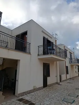 a white building with two balconies and a courtyard at Relax beach San Vito lo Capo in San Vito lo Capo