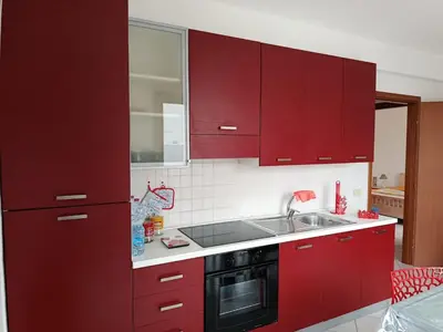 a kitchen with red cabinets and a sink at Relax beach San Vito lo Capo in San Vito lo Capo