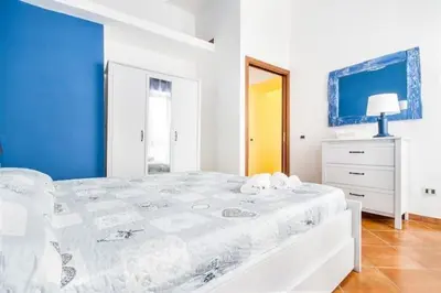 a white bedroom with a white bed and a blue wall at La Casetta del Vicolo in Palermo