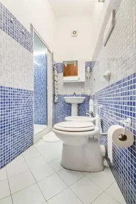 a blue tiled bathroom with a toilet and a sink at La Casetta del Vicolo in Palermo