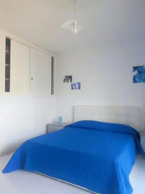 a white bedroom with a blue bed and a window at Cale e Calle in Terrasini