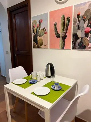 a white table with two chairs and a cactus painting at Casa Fico D'India in Cinisi