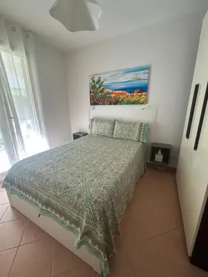 a bedroom with a bed with a painting on the wall at casa NiKa a 150 mt dal mare in Isola delle Femmine