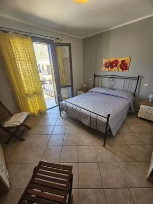 a bedroom with a bed and a sliding glass door at David's Apartment in San Vito lo Capo