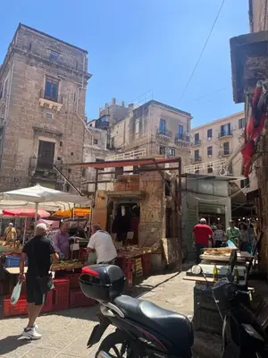 a scooter parked in an outdoor market with people and buildings at Appartamento Casa Florio Mondello in Palermo