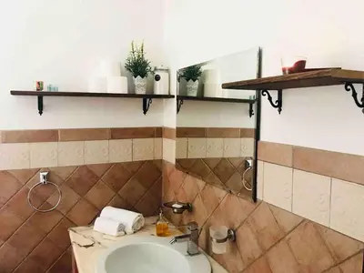 a bathroom with a sink and shelves on the wall at Apartment Via Vittorio Emanuele & Vucciria in Palermo