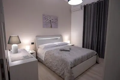 a small white bedroom with a bed and a lamp at Harmony Lux in Bagheria