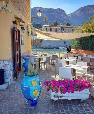 a patio with tables and chairs and vases with flowers at Seaside in Santa Flavia