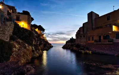 a river with buildings on the side of a cliff at Seaside in Santa Flavia