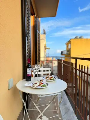 a table with plates of food and wine glasses on a balcony at Seaside in Santa Flavia