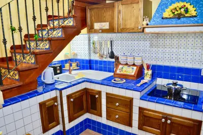 a blue tiled kitchen with a sink and a staircase at Home sweet home in Santa Flavia