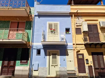 a blue building with a balcony with flowers on it at Casa Mo' in Isola delle Femmine