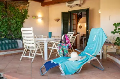 a pair of chairs and a hat sitting on a patio at Clizia Holiday in Campofelice di Roccella