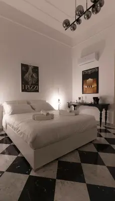 a white bedroom with a large bed and a piano at Large two-room apartment within walking distance of the Teatro Massimo in Palermo