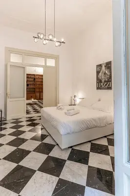 a white bedroom with a black and white checkered floor at Large two-room apartment within walking distance of the Teatro Massimo in Palermo