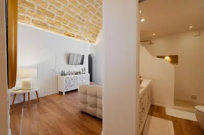 a living room with a stone wall and a bathroom at Sea House - Suite vista mare in Terrasini