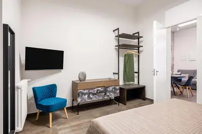 a bedroom with a tv and a blue chair at Casta Diva Fervore Apartments Self Check-in in Palermo