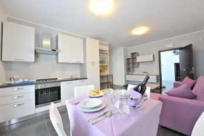 a kitchen and living room with a table and purple chairs at Case Mistretta in Altavilla Milicia