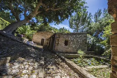 an old stone building sitting on top of a field at Casa Portico, con piscina in comune in Terrasini